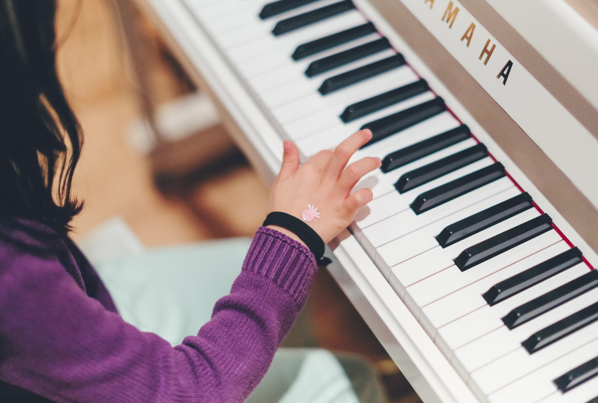 Une enfant joue sur un piano Yamaha