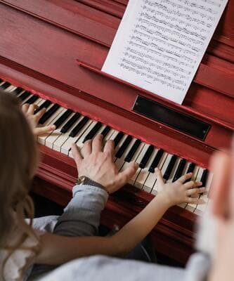 Les mains d’une adulte et d’un enfant sur un piano